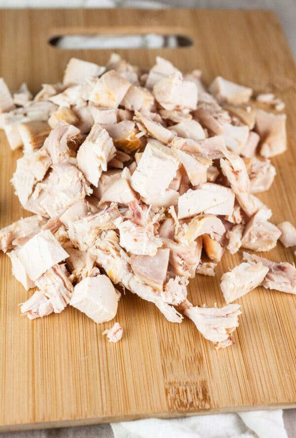 Diced rotisserie chicken on wooden cutting board.