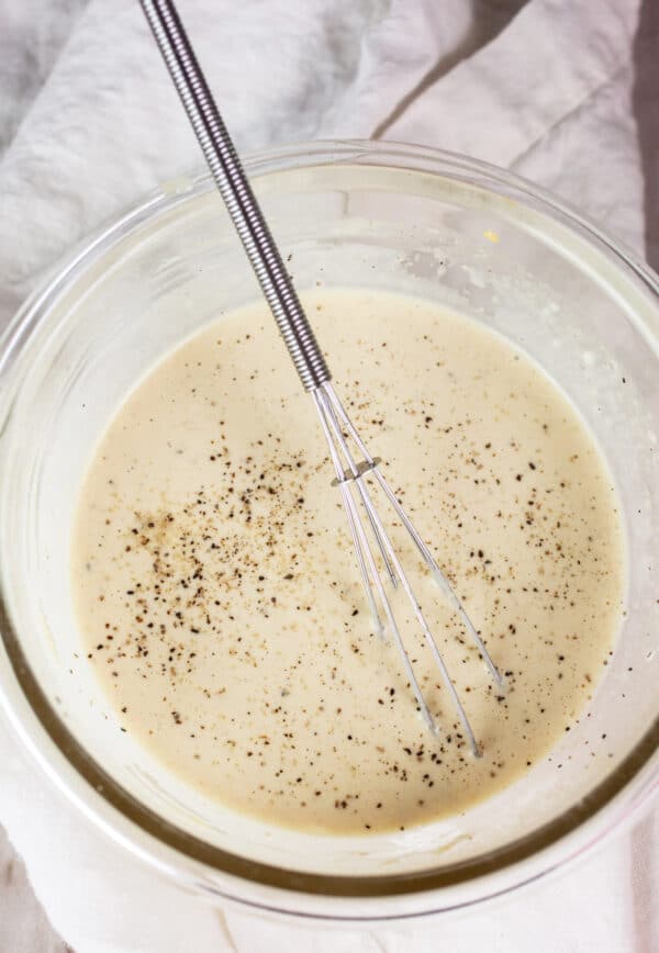 Mayo Dijon mustard dressing in small glass bowl with whisk.