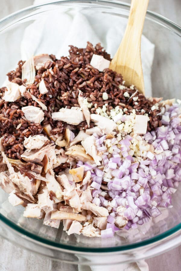 Cooked wild rice, diced rotisserie chicken, and shallots in glass bowl.