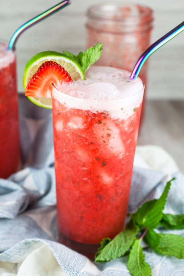 Strawberry mojito mocktails with fresh mint and limes in tall glasses with metal straws.