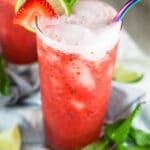 Virgin strawberry mojitos with fresh mint and limes in tall glass with metal straw.