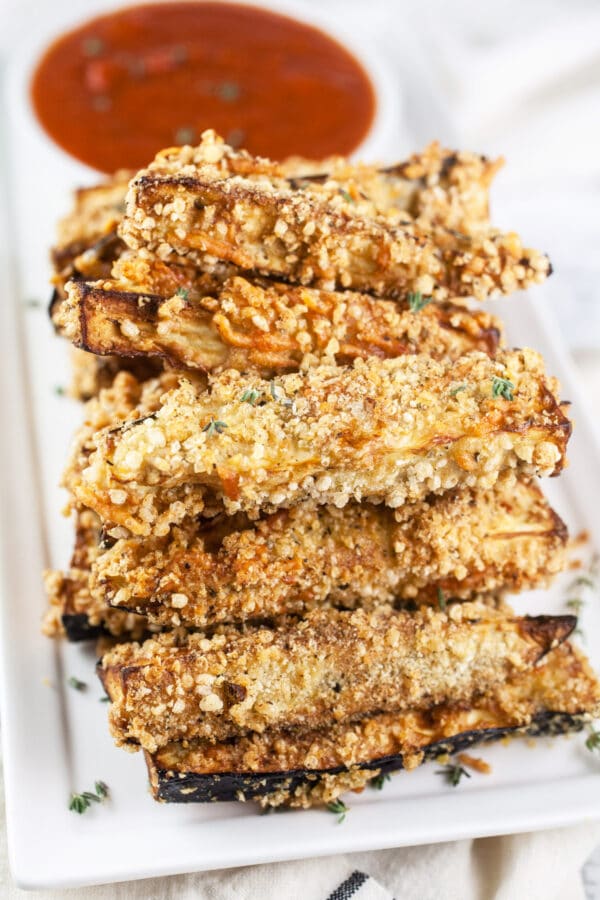 Eggplant Parmesan fries with marinara sauce on white serving platter.