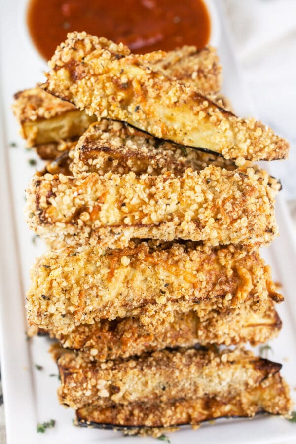 Eggplant Parmesan fries stacked on white platter.