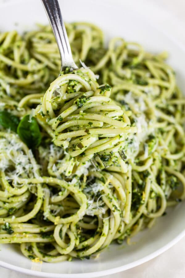 Spaghetti noodles tossed in sauce wrapped around fork in white bowl.