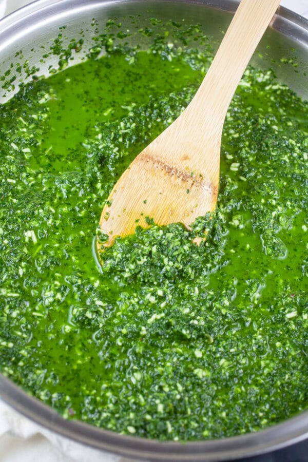 Green pasta sauce with broth in skillet.