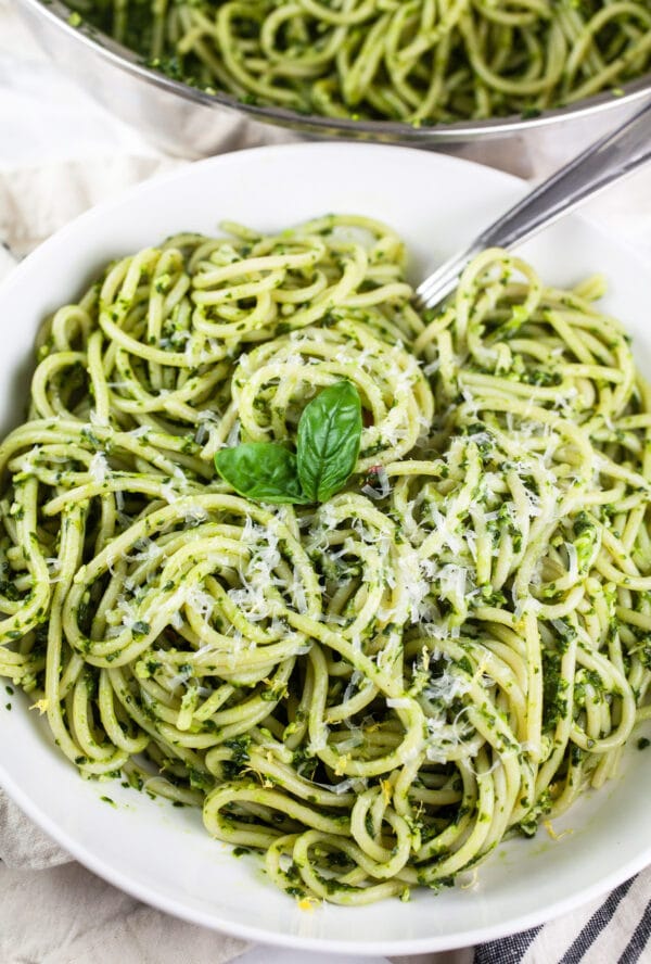 Spaghetti noodles with spinach basil pasta sauce in white bowl with fork.