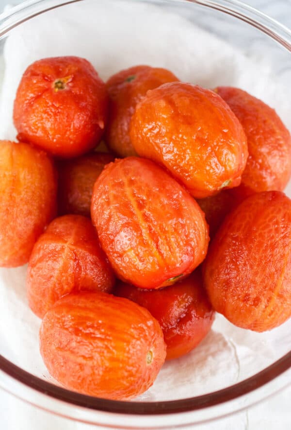 Blanched and peeled Roma tomatoes in large glass bowl.