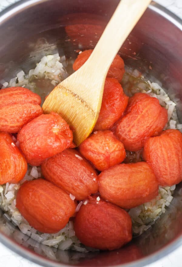 Garlic, onions, and blanched Roma tomatoes sautéed with olive oil in metal pot.