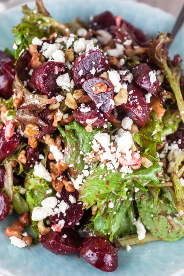 Pickled beet, balsamic, feta, and walnut salad in blue serving bowl with spoon.