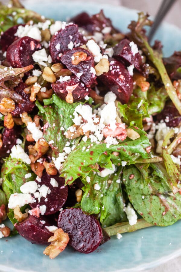Pickled beet, greens, feta, and walnut salad with balsamic vinaigrette in blue bowl.