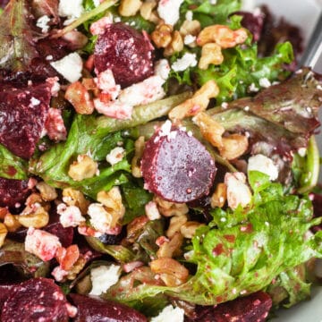 Pickled beet, balsamic, feta, and walnut salad in white bowl with fork.