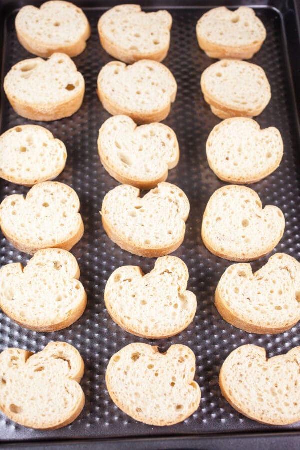 Unbaked sliced baguette on baking sheet.