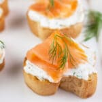 Smoked salmon lemon dill crostini on white serving platter.