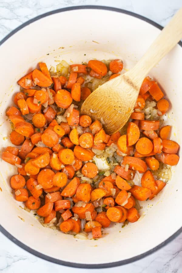 Sliced carrots sautéed in white cast iron Dutch oven.