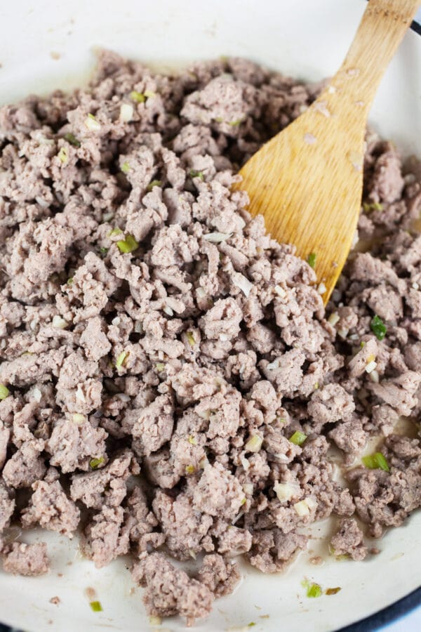 Cooked ground turkey in white cast iron skillet.