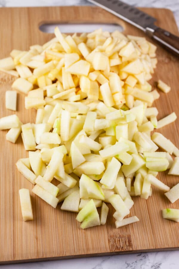 Peeled and diced Granny Smith and Gala apples on wooden cutting board.