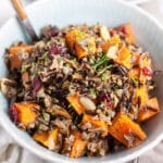 Roasted butternut squash harvest wild rice salad in blue bowl with fork.