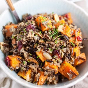Roasted butternut squash harvest wild rice salad in blue bowl with fork.