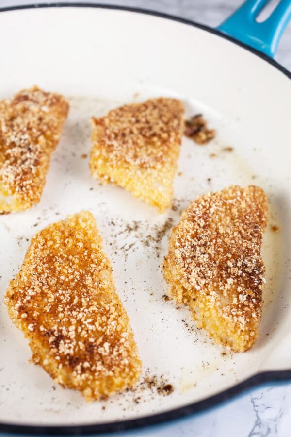 Breaded kohlrabi wedges fried in white cast iron skillet.