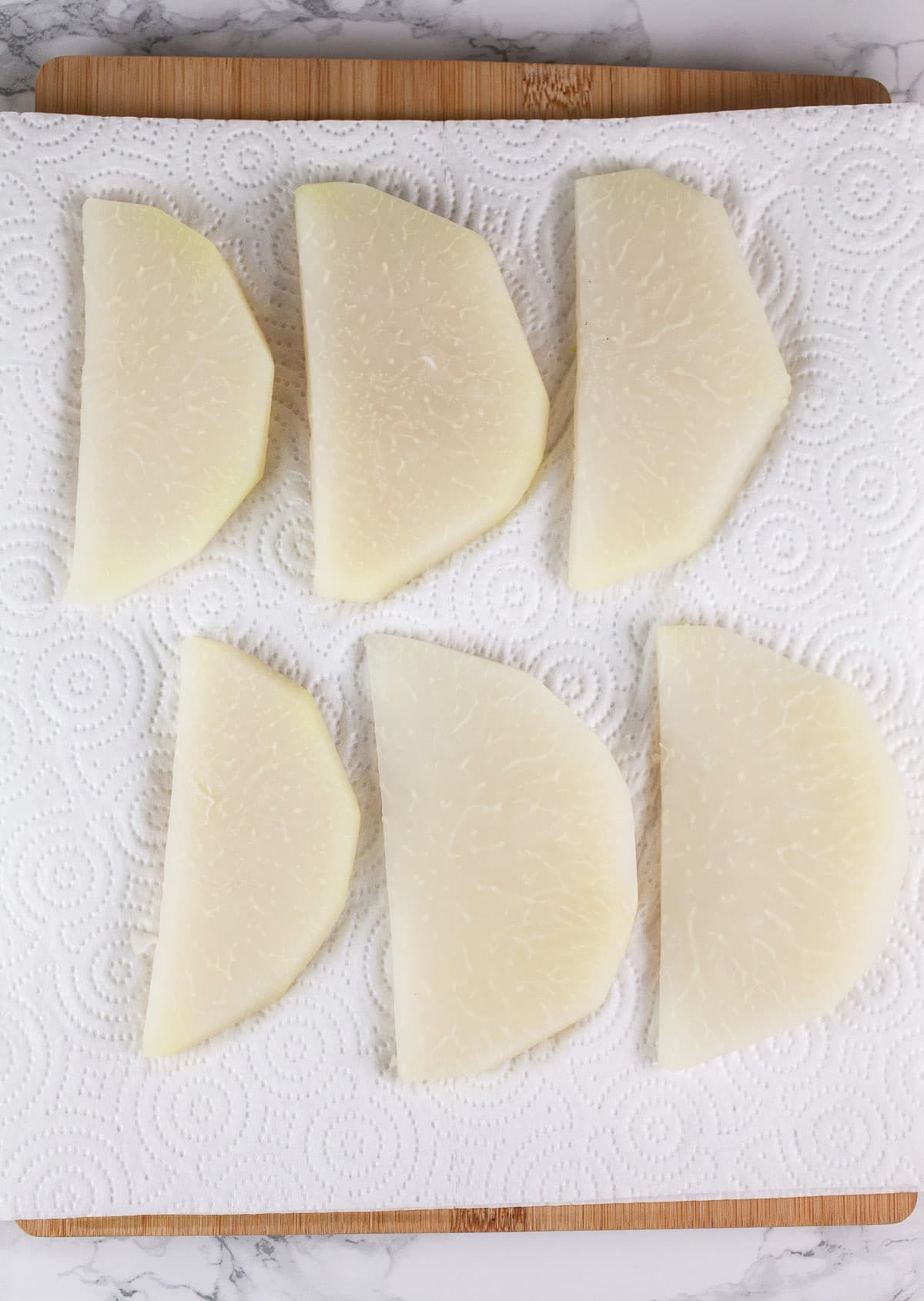 Parboiled kohlrabi slices on paper towel.