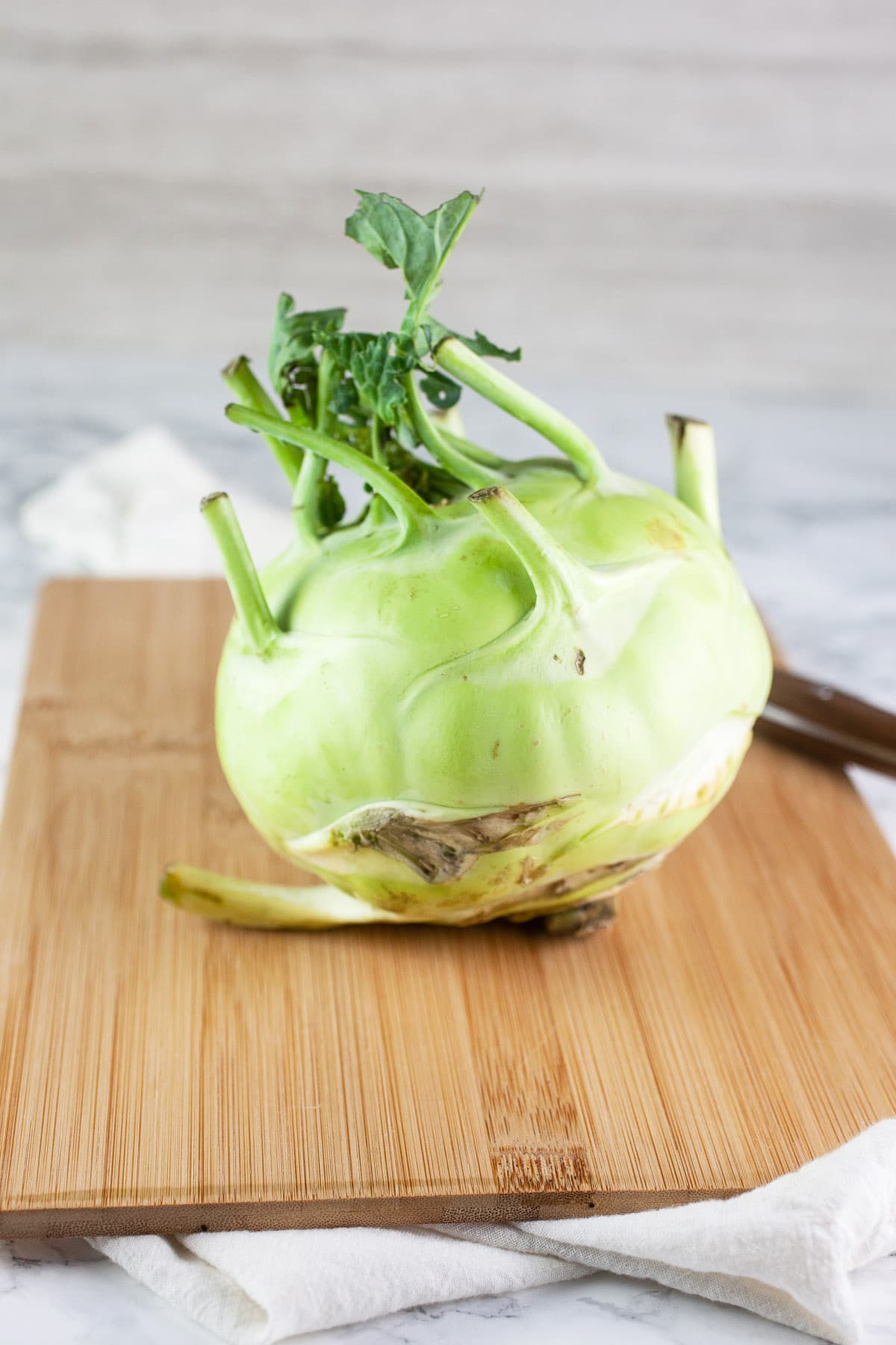 Kohlrabi on wooden cutting board with knife.