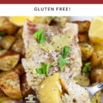 Baked pesto cod and potatoes with fork garnished with fresh basil and lemon wedges.