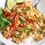 Ground chicken rice bowl with red bell peppers, fresh mint, and lime wedge in white bowl.