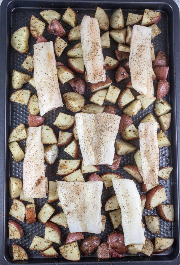 Uncooked cod and diced potatoes on baking sheet.