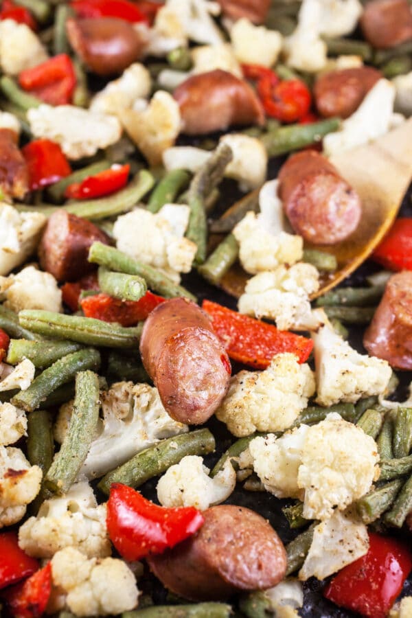 Roasted chicken sausage and vegetables on baking sheet.