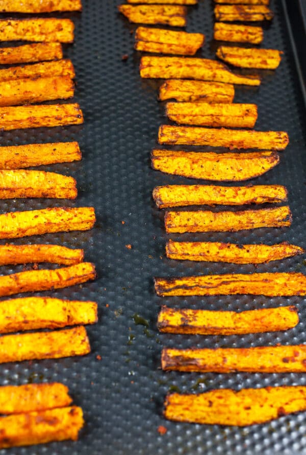 Baked butternut squash fries on baking sheet.