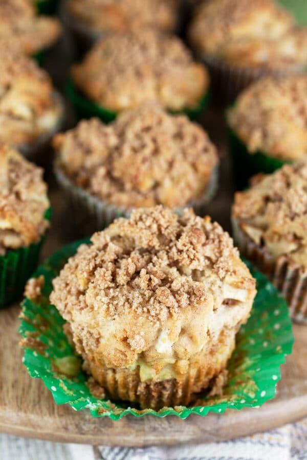 Baked apple muffins with streusel on wooden board.
