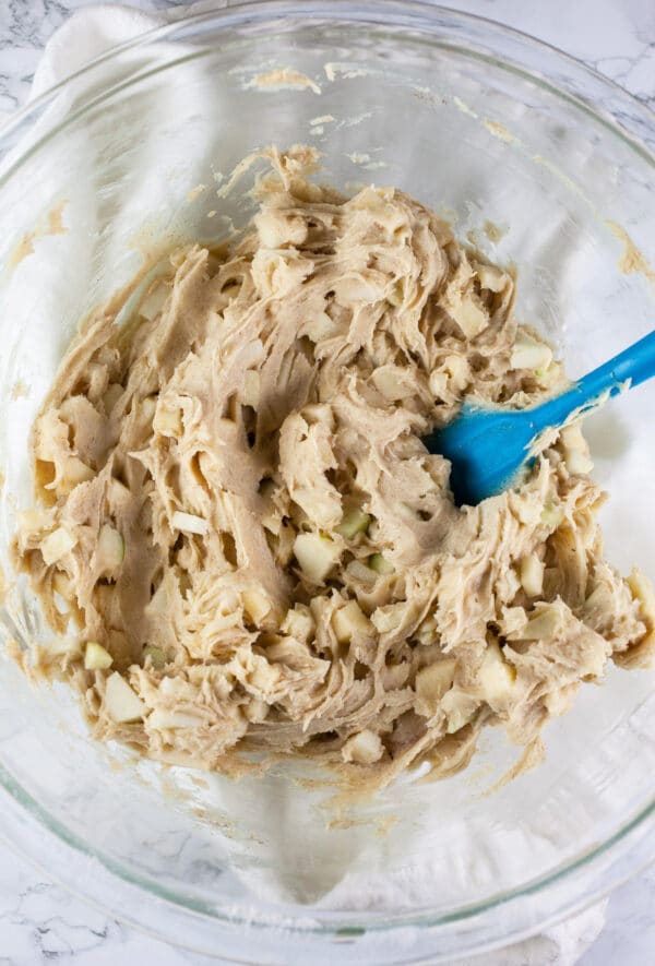 Muffin batter combined with diced apples in large glass mixing bowl.