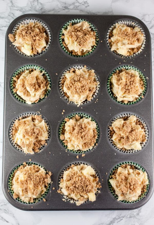 Unbaked muffins with streusel topping in muffin tin.