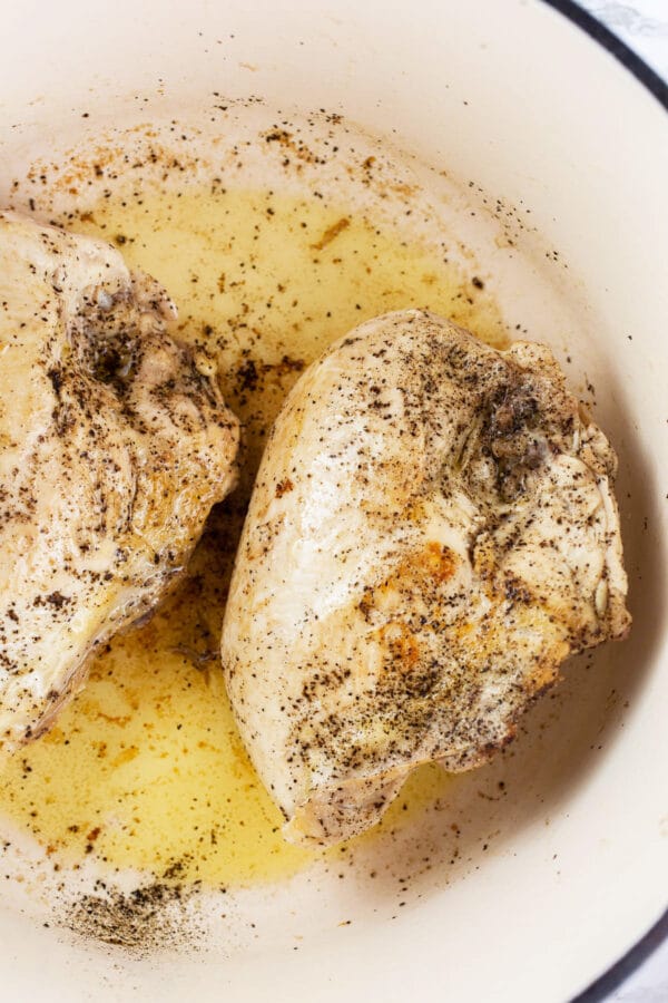 Bone-in chicken breasts sautéed in white Dutch oven.