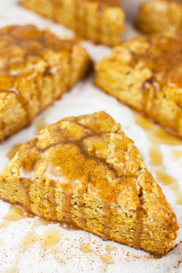 Maple glazed gluten free pumpkin scones on white surface.