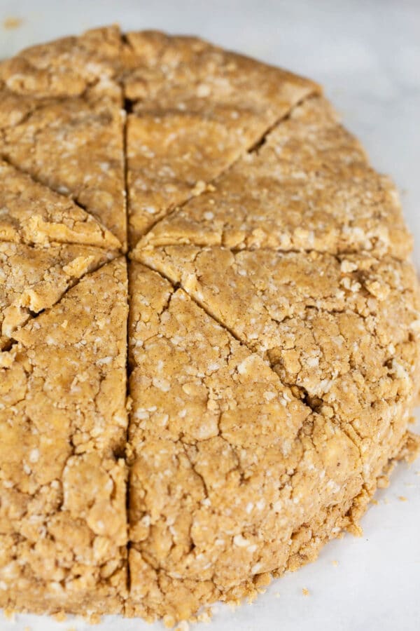 Pumpkin scone dough cut into equally sized wedges.