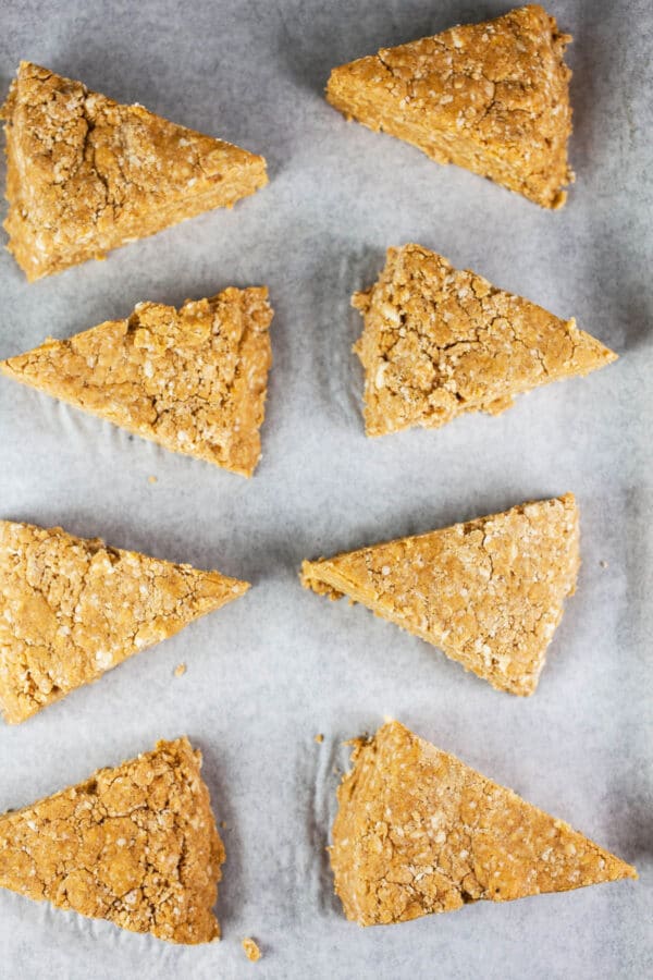 Unbaked pumpkin scones on parchment paper-lined baking sheet.