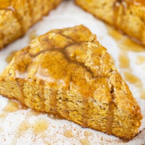 Maple glazed gluten free pumpkin scones on white surface.