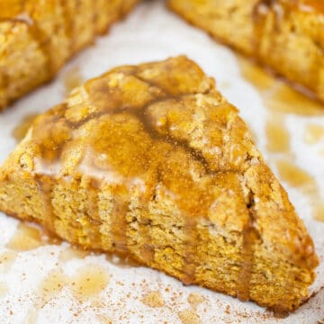 Maple glazed gluten free pumpkin scones on white surface.