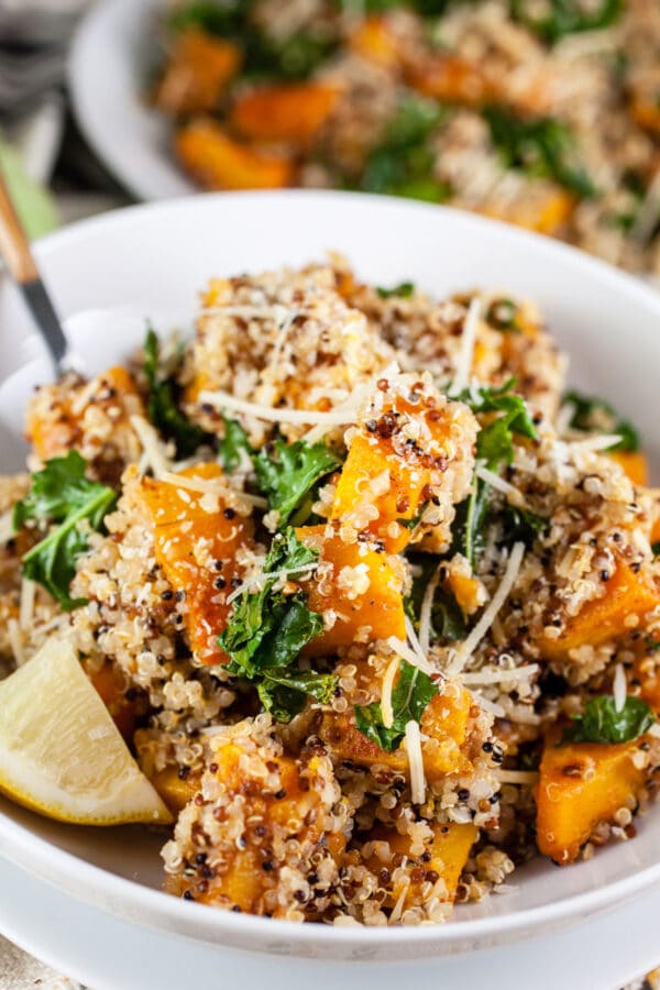 Roasted butternut squash quinoa kale salad in white bowls.