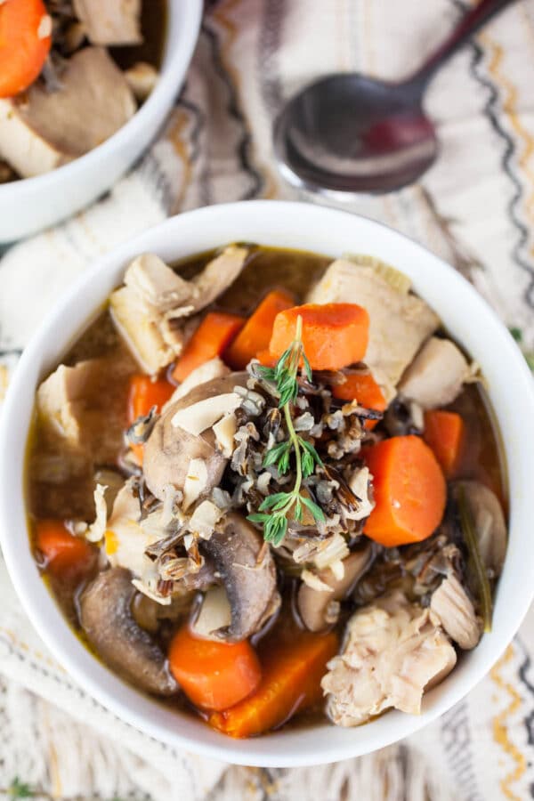 Wild rice turkey soup in small white bowl with spoon.