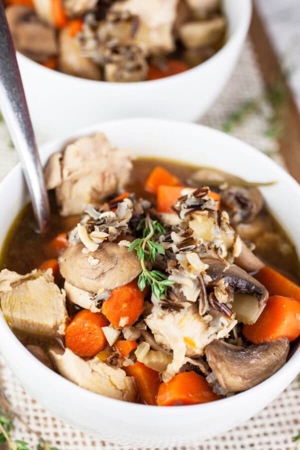 Wild rice turkey soup in small white bowls with spoon.