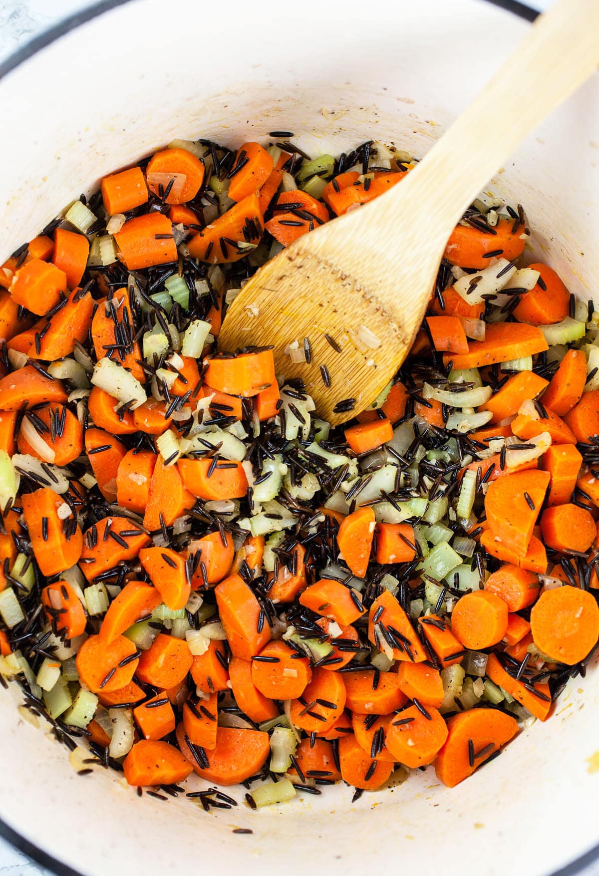 Wild rice, carrots, garlic, onions, and celery sautéed in white Dutch oven.