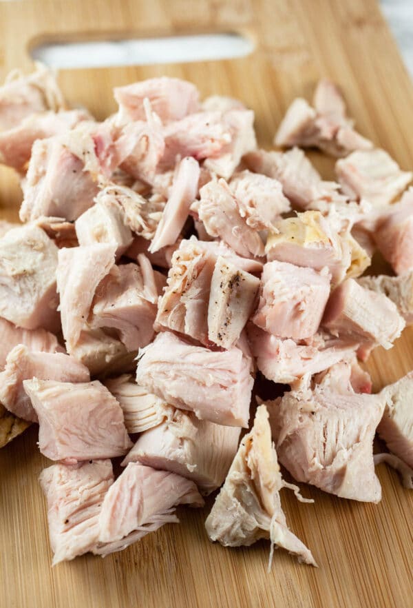 Chunks of roasted turkey on wooden cutting board.