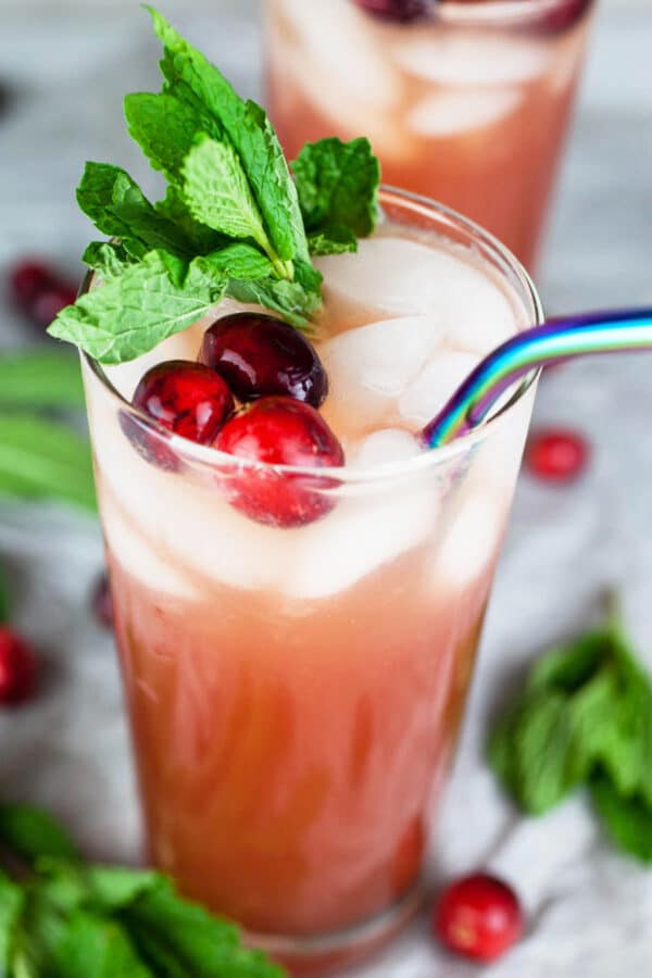 Cranberry apple cider mocktail in highball glass with fresh mint and cranberries.