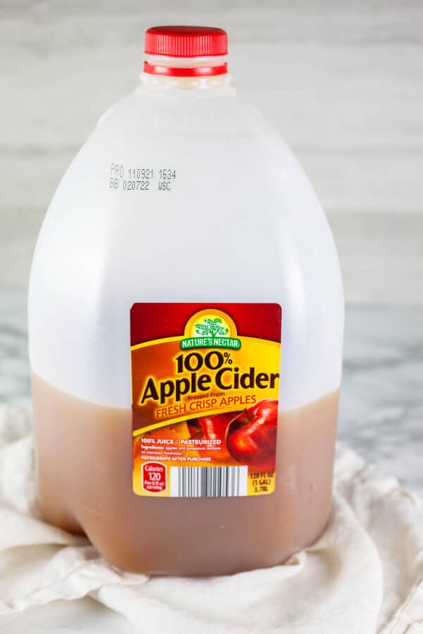 Apple cider in plastic jug on white and grey surface.