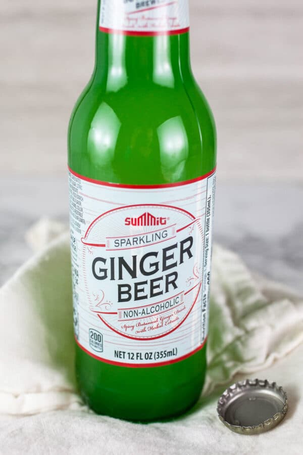 Ginger beer in green glass bottle on white and grey surface.