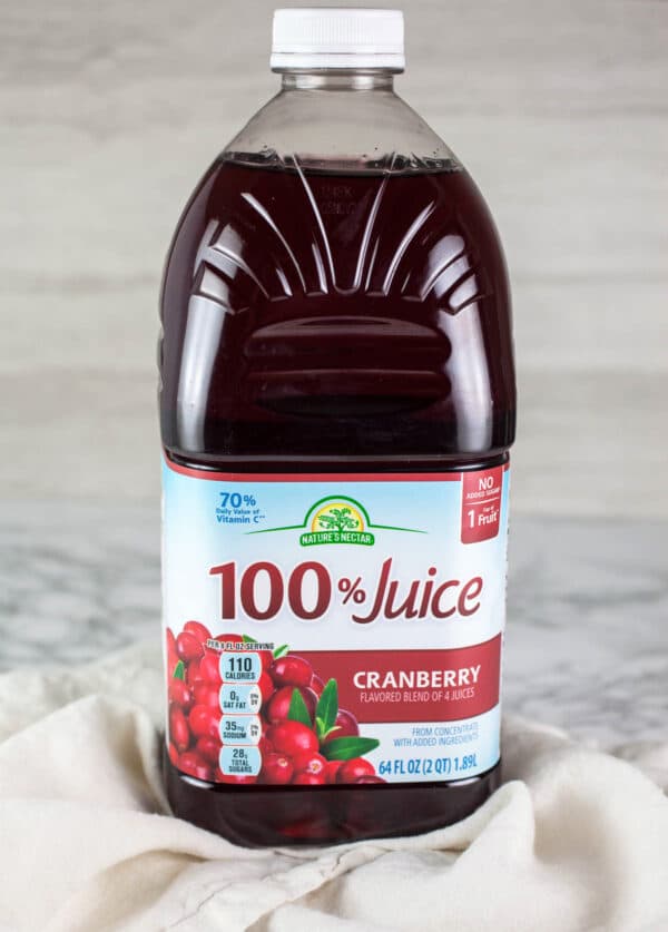 Cranberry juice in plastic jug on white and grey surface.