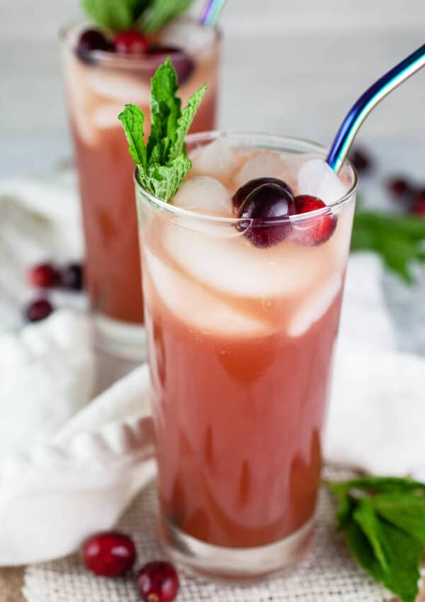 Cranberry apple cider ginger beer mocktails in highball glasses with straws.