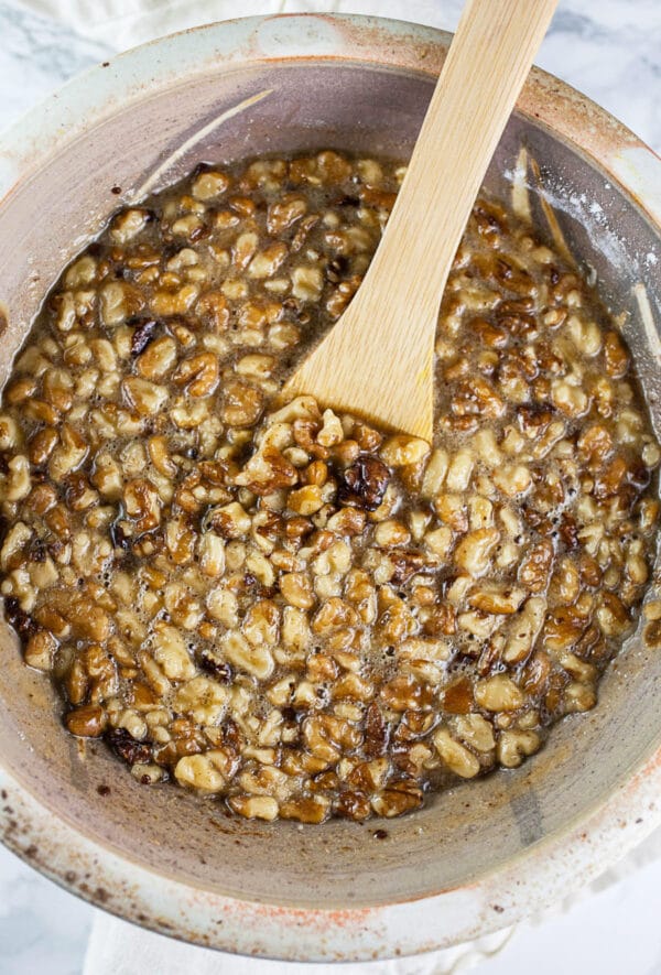 This Maple Bourbon Walnut Pie puts a twist on the traditional pecan pie. It's sweetened with maple syrup and kicked up with a shot of bourbon. This homemade pie is one of my favorite dessert recipes. I will take this maple bourbon walnut pie over pecan any day! #pie #maple #bourbon #walnut #thanksgiving Maple walnut pie filling in ceramic bowl.